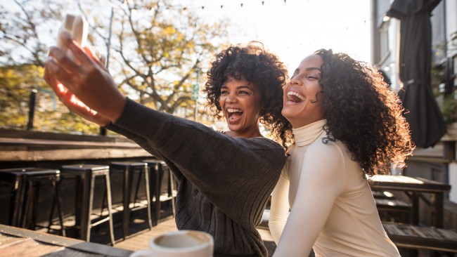 duas mulheres sorrindo tirando selfie