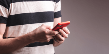 Homem de camisa listrada com celular nas maos