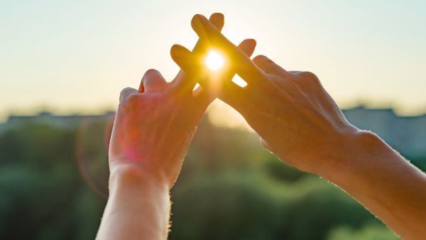 Pessoa fazendo sinal de hashtag sobre a luz do sol