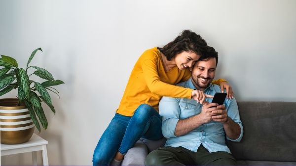 Casal feliz olhando memórias passadas no celular para compartilhar tbt no Instagram