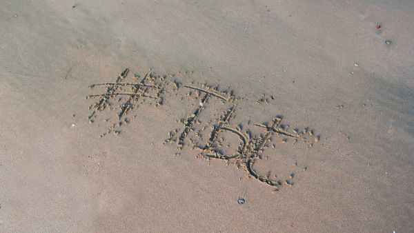 Hashtag tbt desenhada na areia da praia em momento de lazer