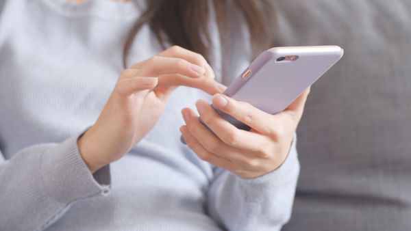 Mulher com blusa cinza compartilhando post de tbt no Instagram pelo celular