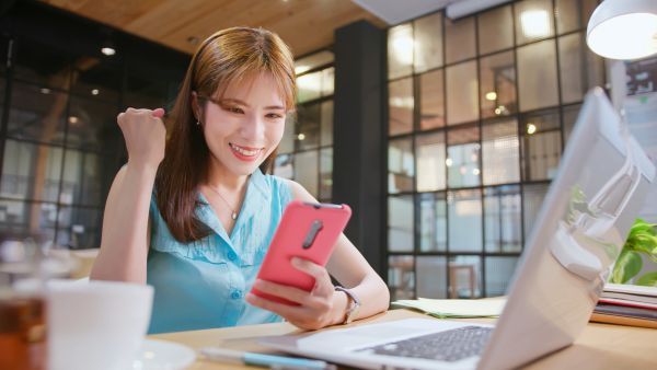 Mulher olhando para celular feliz com ganhos financeiros conquistados no Instagram