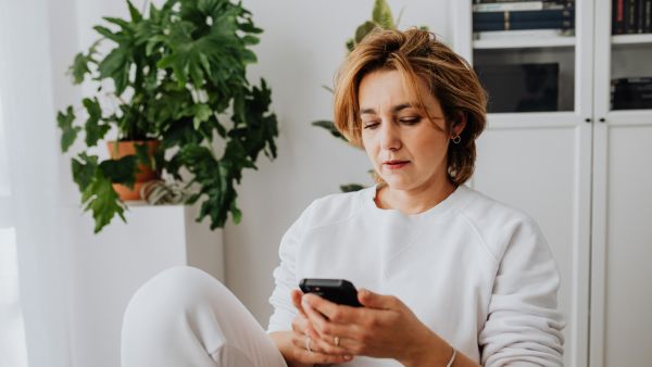 Mulher olhando para celular procurando formas de ganhar dinheiro no Instagram