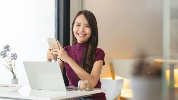 Mulher no escritório sorrindo segurando o celular