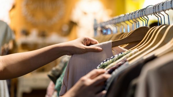 Cliente olhando peças de roupas em brécho