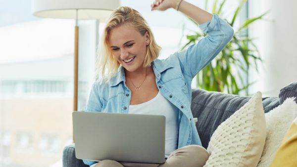Mulher comemorando após ver o crescimento do seu perfil no Instagram em seu notebook
